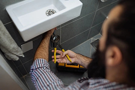 Illustration - Ihr Experte für schönes Wohnen - Handwerker installiert Handwaschbecken im Badezimmer.